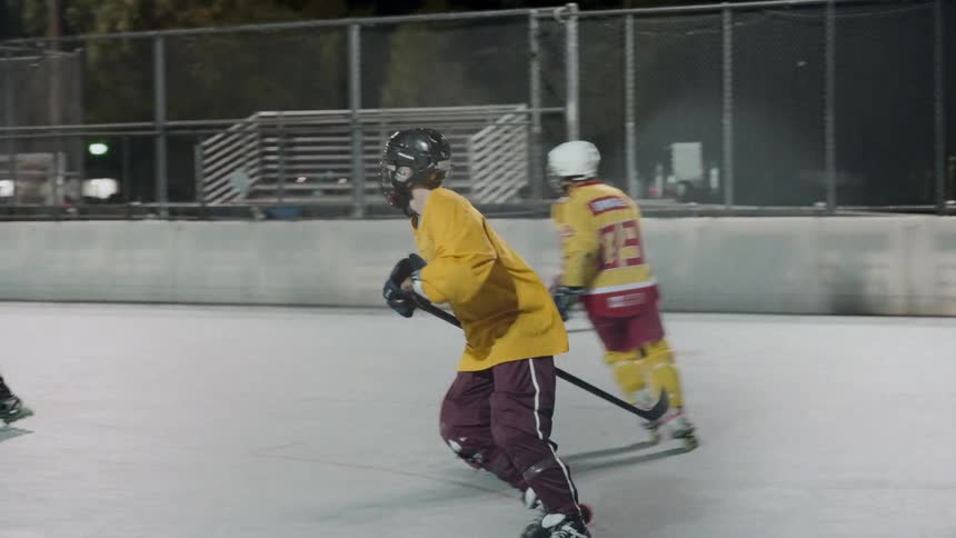 Hockey players are skating on the ice at night