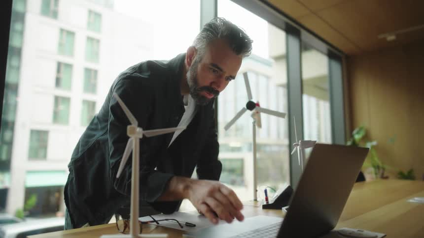 Man analyzes something on his laptop while working on a wind energy project