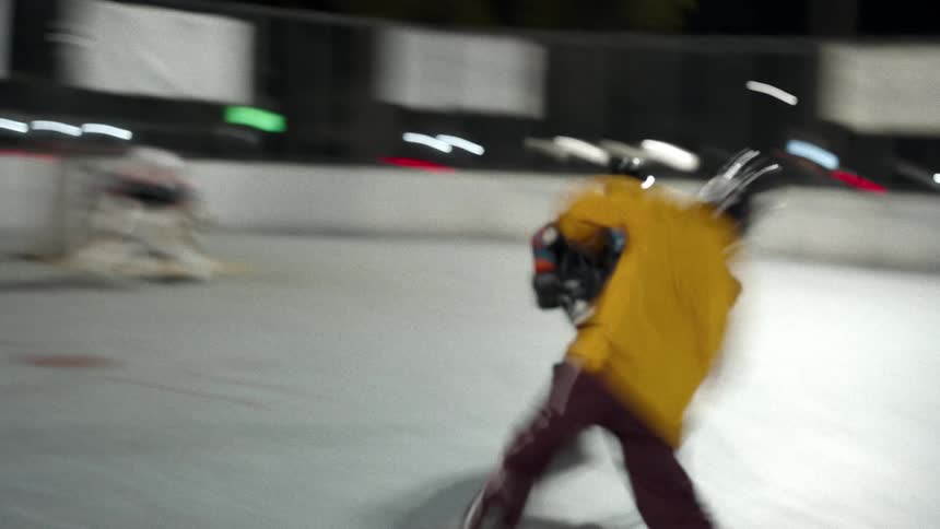 Street hockey players play a game on an outdoor court at night