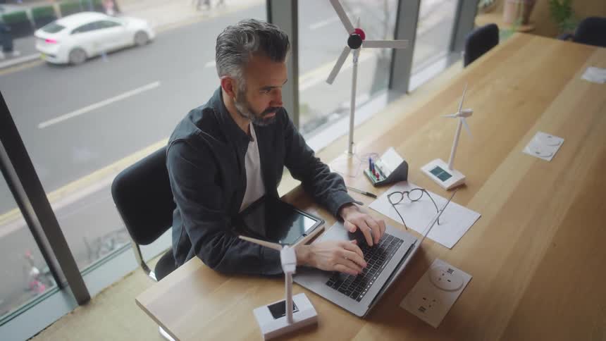 A man is typing on his laptop in the conference room
