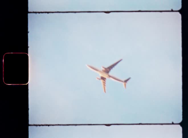 An airplane soars through the air beneath thin white clouds