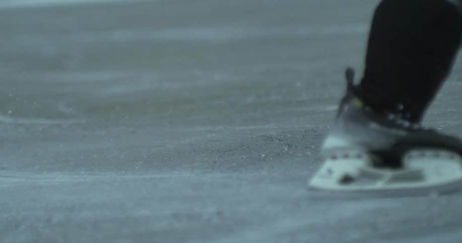 Hockey player with ice hockey stick skating on an outdoor rink