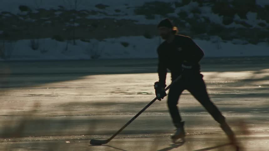 Two men are playing hockey on the frozen lake