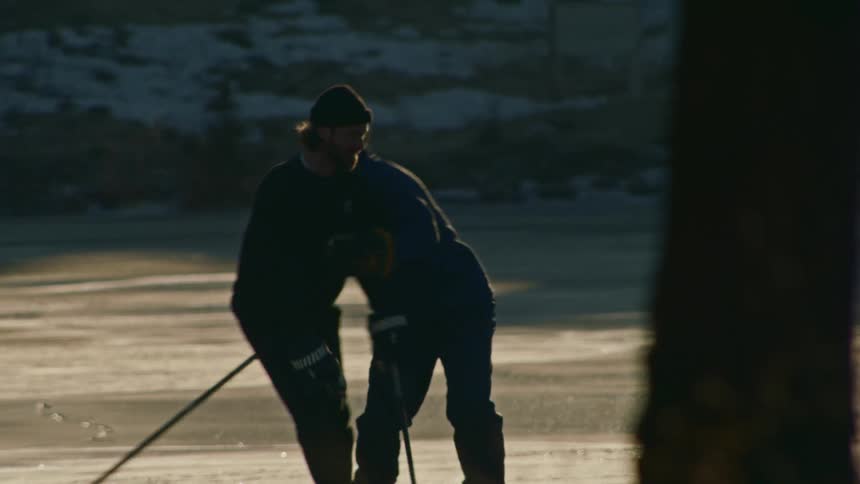 Two men playing hockey in an outdoor game