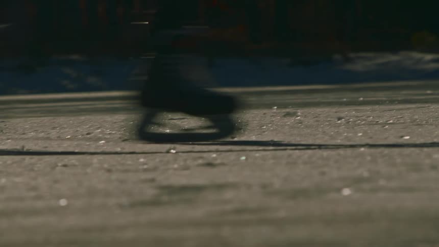 Two people playing hockey on the ice on a sunny day