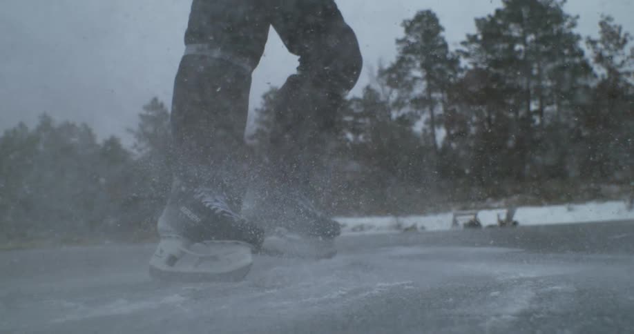 Hockey player brakes sharply on the ice kicking up a cloud of snow during the game