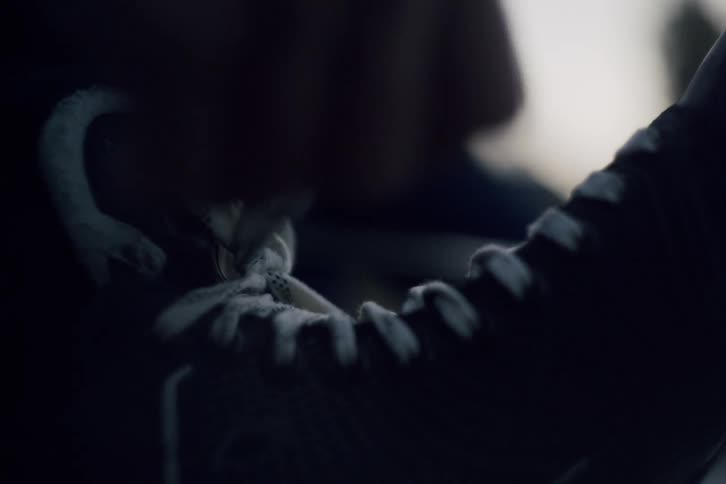 A person is lacing up his boot