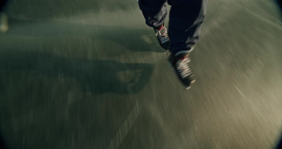 A hockey players feet and skates are shown as they glide across the ice with a hockey stick partially visible