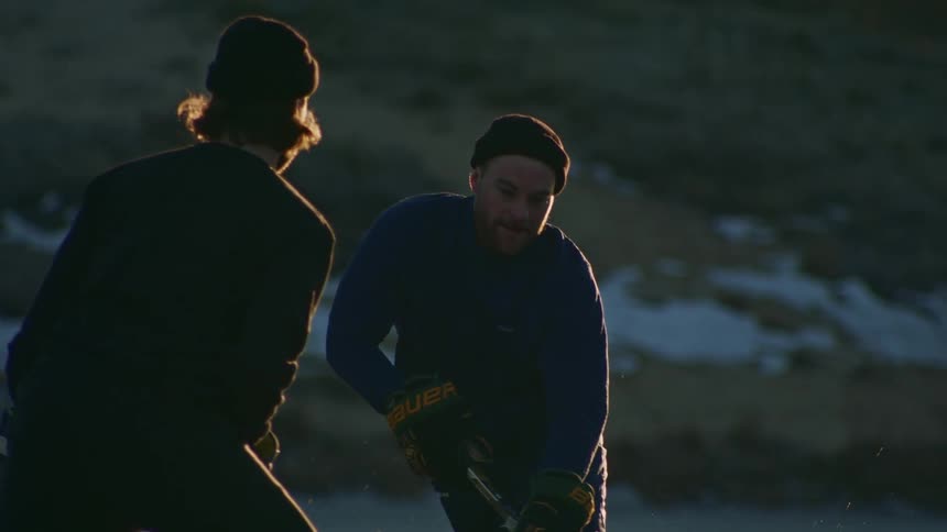 Two players play an outdoor ice hockey game