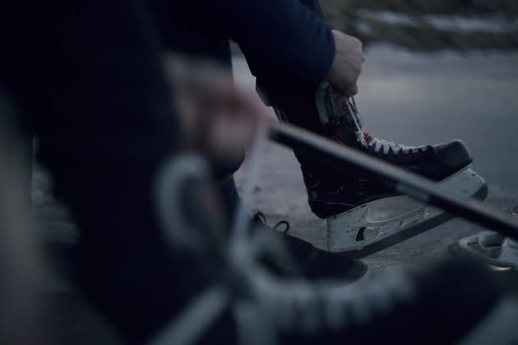Lacing up hockey skates outdoors on a frozen pond
