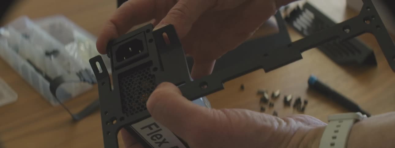 Hands mounting a computer power supply on a stand