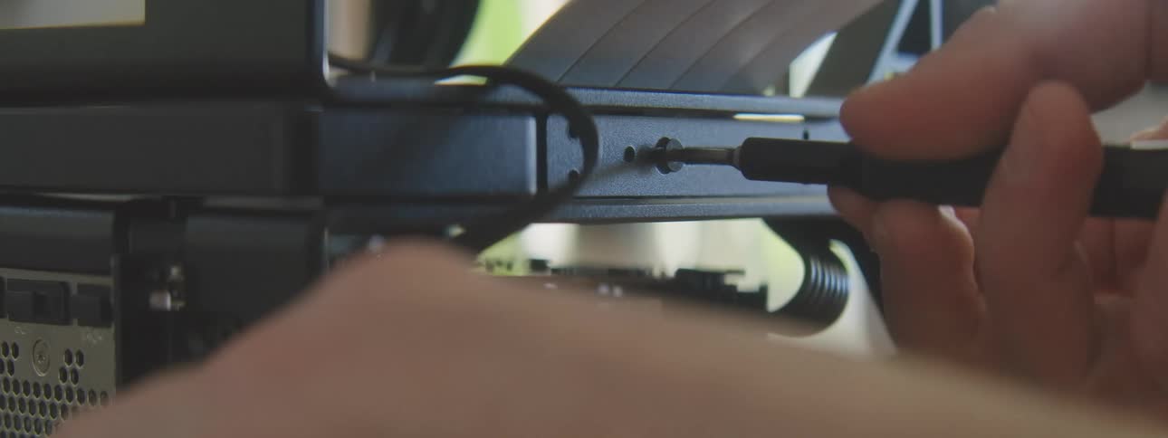 Person uses a screwdriver to secure a component in an open computer case