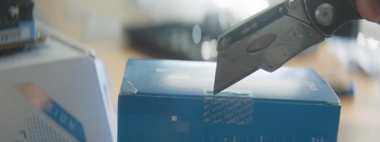 A man opens a small box with a box cutter
