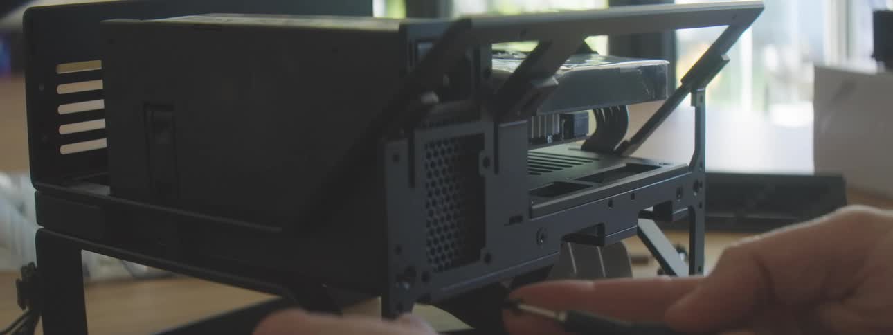 Person assembles a compact computer by attaching components to the frame