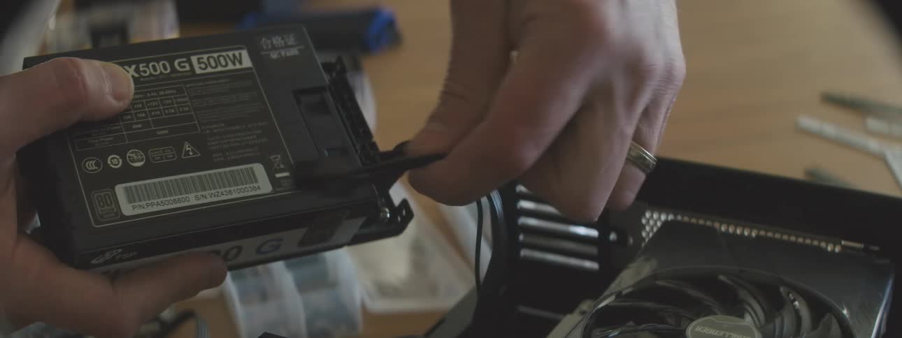 Pair of hands connecting cables to a computer power supply