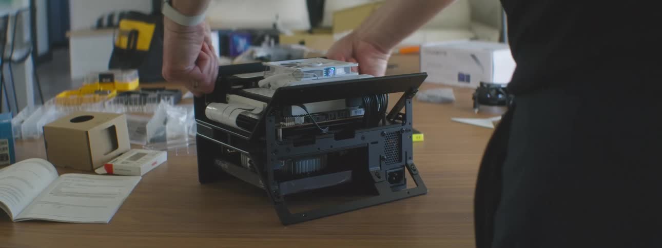 A person leaving a technological object that is on a standing wooden table and then leaves