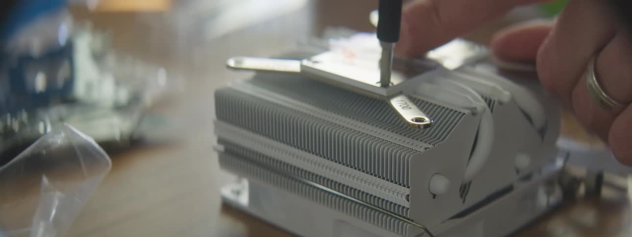 Hand tightens a screw on a heat sink while assembling an electronic component