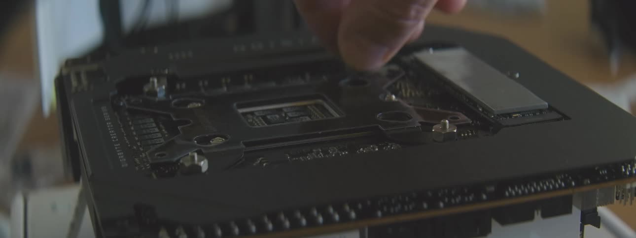 A closeup shot shows a hand manipulating a component on a computer motherboard