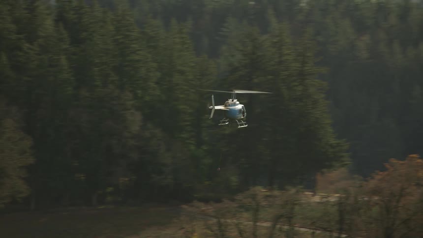A chopper flying over a forest and agricultural land