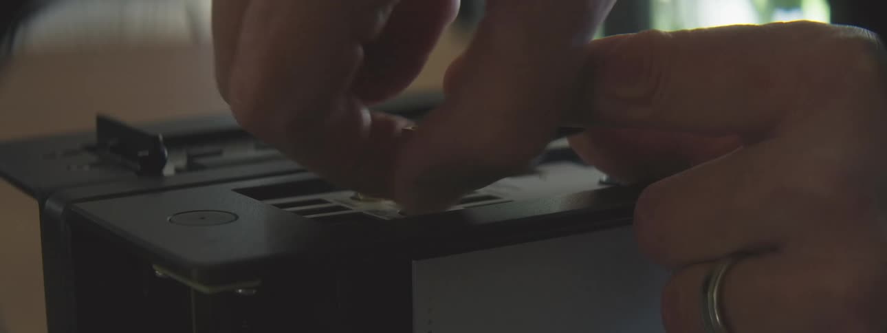 Person attaches gold screws to the frame of a computer during assembly