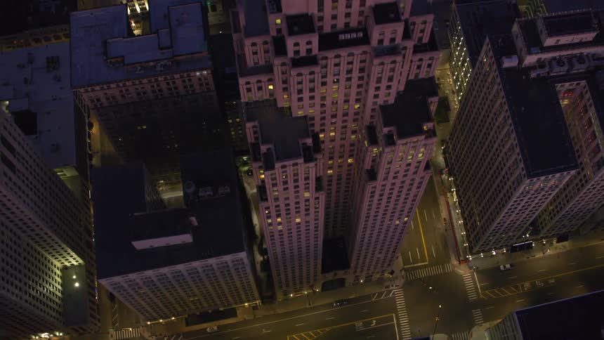 Aerial view of a city center at night with illuminated skyscrapers and busy streets