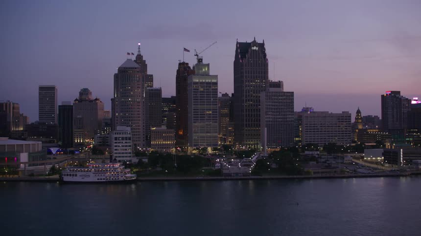 City skyline reflected in the river at dusk with buildings illuminated against the sky