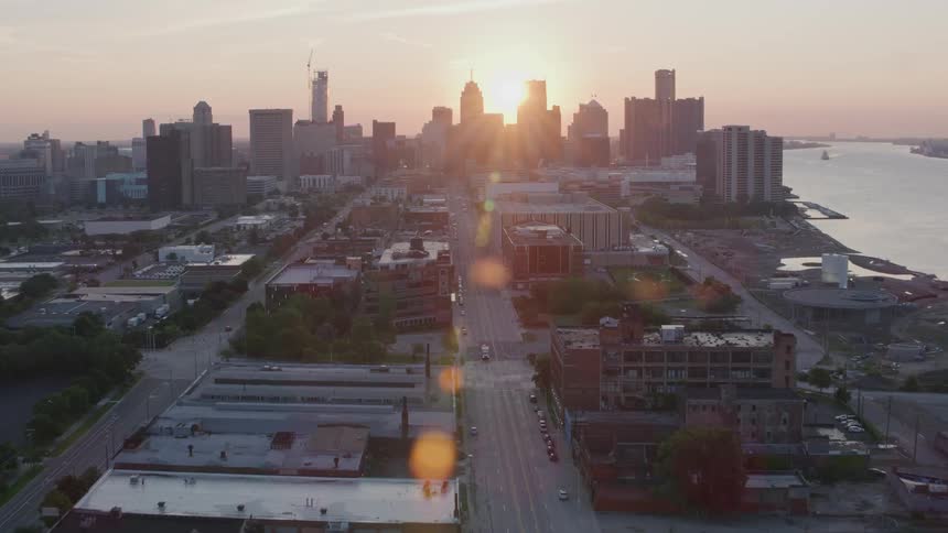 Aerial view of a city at dawn with the sun rising between the skyscrapers