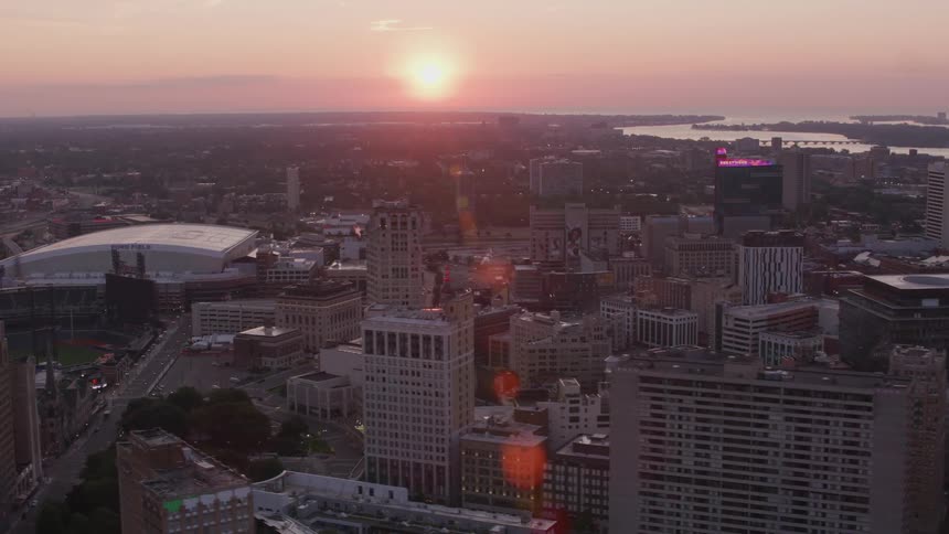 Aerial view of a city at sunset with skyscrapers and orange reflections on the horizon
