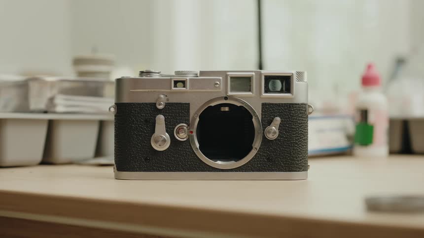 An old gray and black camera on a wooden table