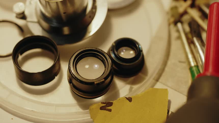 Paintbrushes and round lenses in various sizes rest on a table