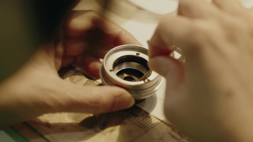 Person delicately handles an optical component with tweezers