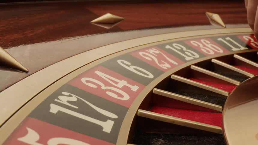 Picking up white marble from roulette wheel as its slowly spinning clock wise