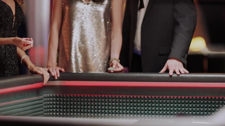 Woman at a table with other people around and playing dice in a casino game