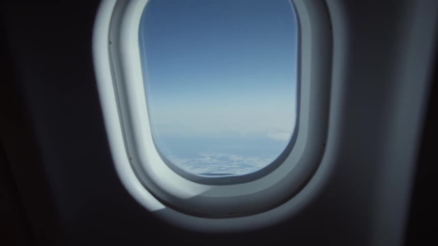 Aerial view of the horizon and the wing of an airplane from one its windows