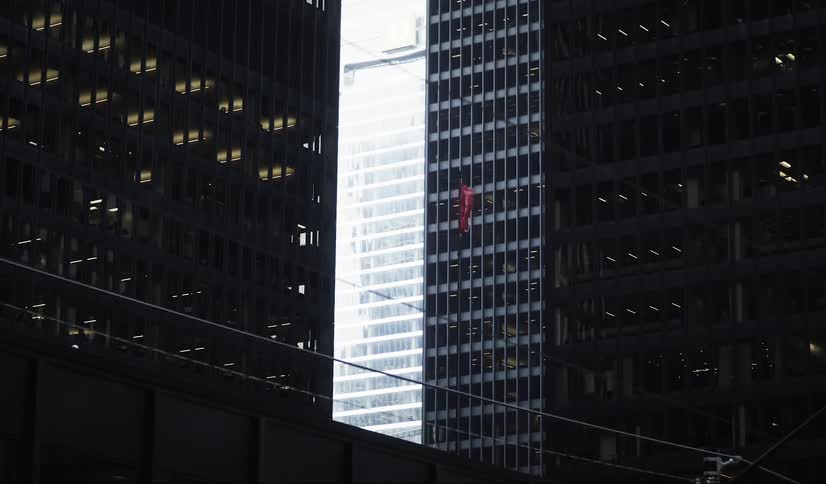 Canadian flag flutters between mirrored skyscrapers in an urban center
