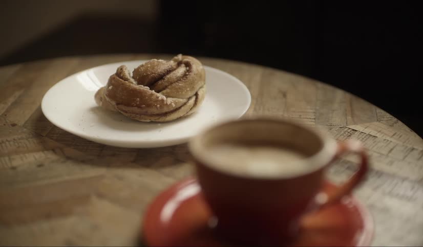 Coffe in a red tea cup and pastry on white plate sitting on a round wood table