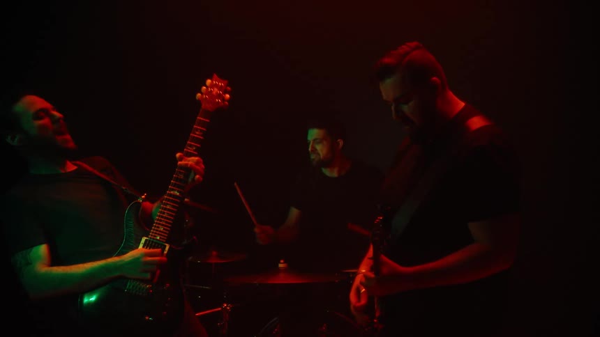 Three men playing drums and guitar in a performance