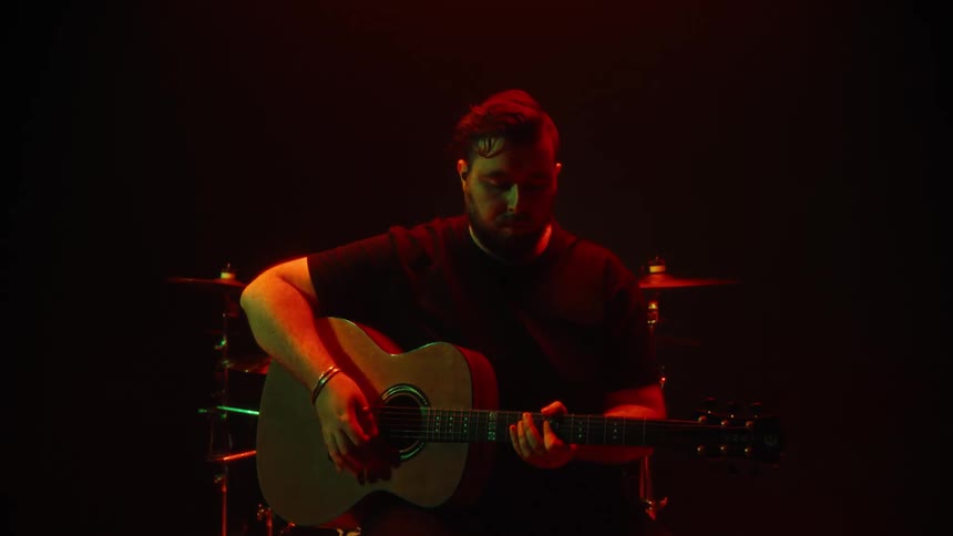 Man in a solo studio playing guitar