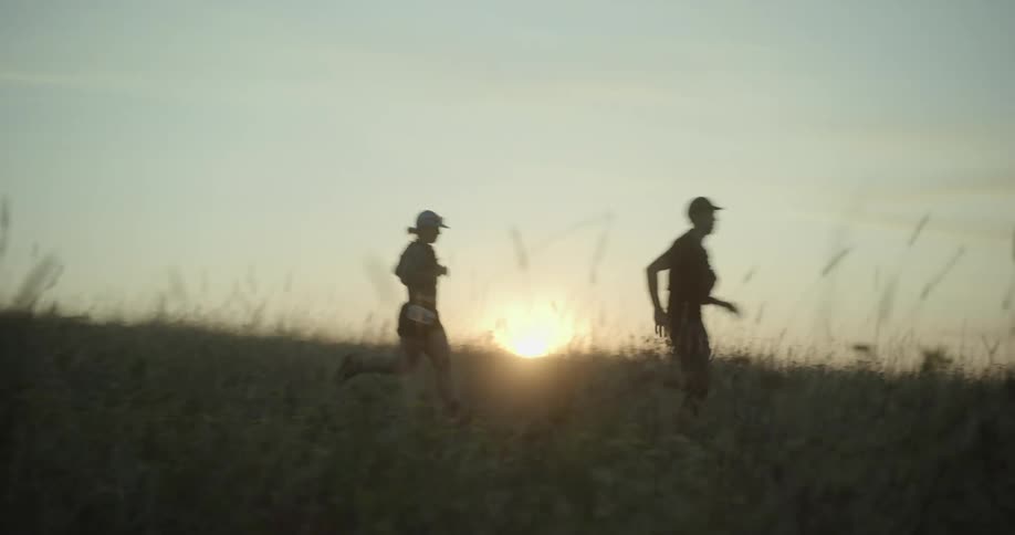 Group of runners cross an open field at dusk