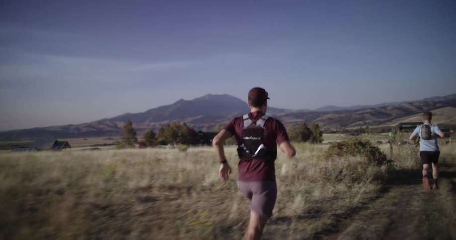 Two men running down a mountain trail