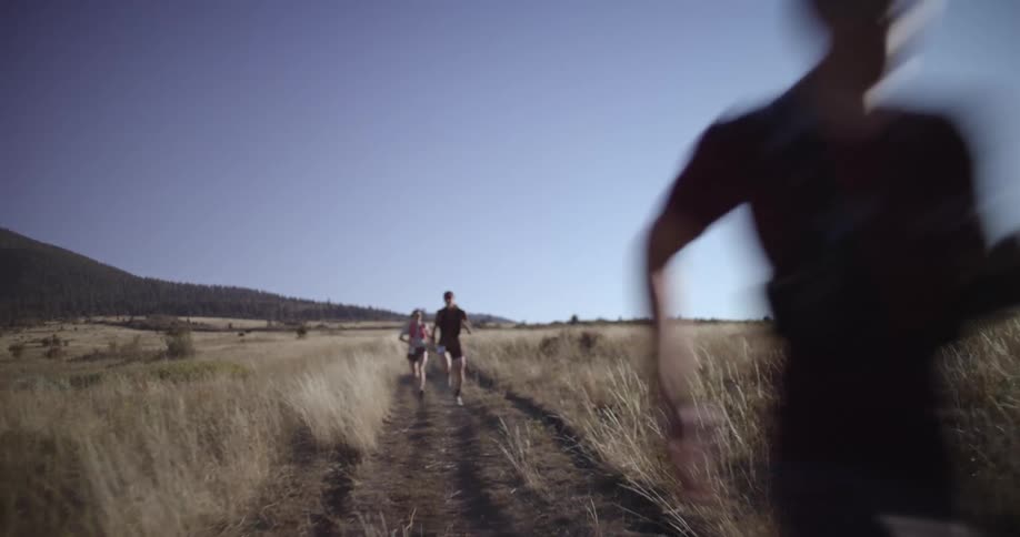 A group of people are competitively running in a grassland on a sunny summer day