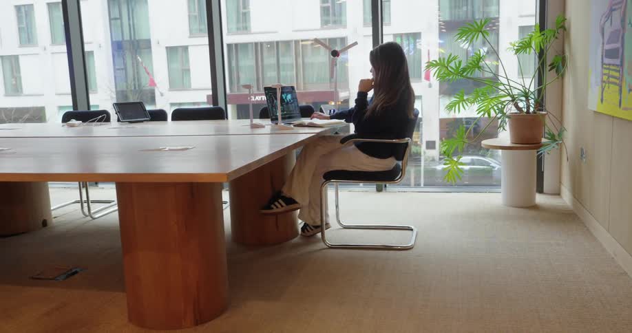 A woman sits in a conference room and works on her laptop