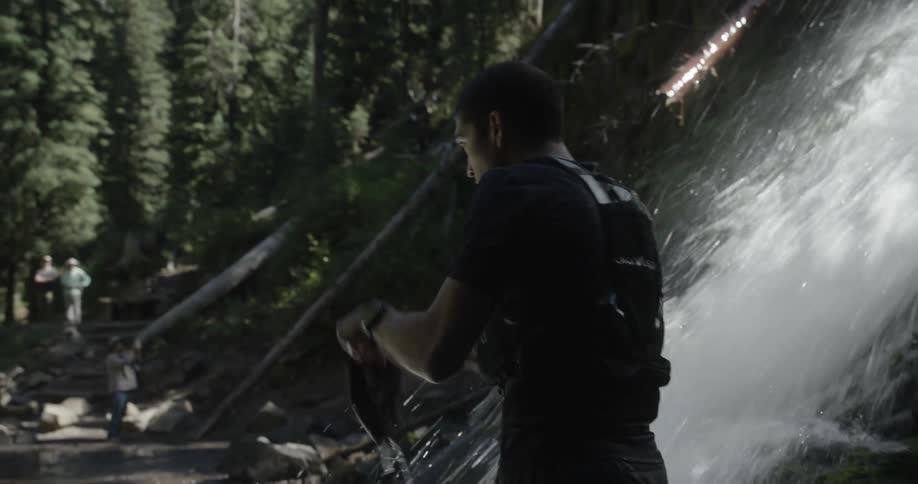 Man wetting his cap in a waterfall