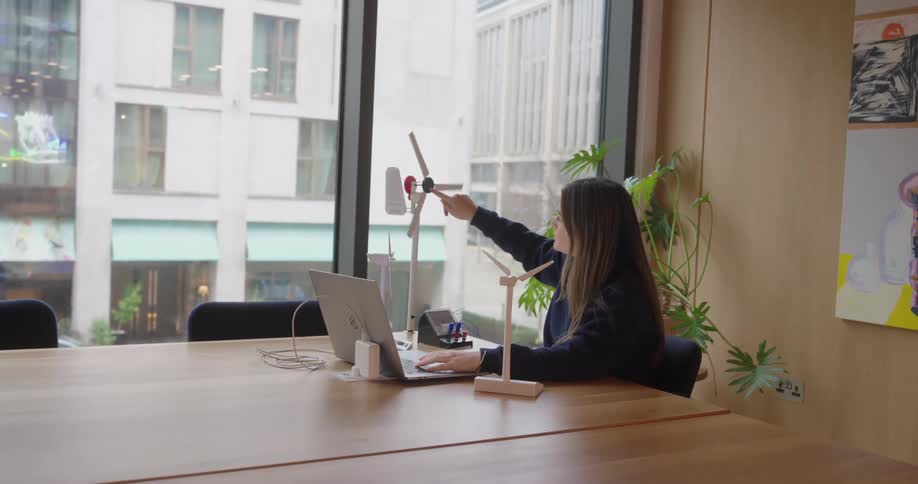 Woman works in a modern office while adjusting a wind turbine model