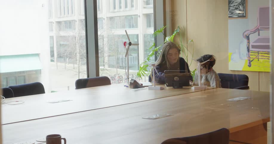 Woman and child sitting at an office desk interacting in front of a tablet