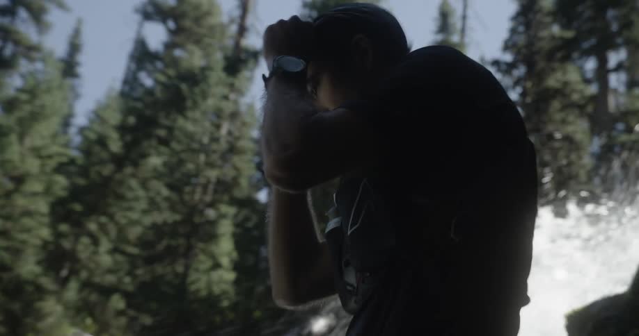 Competitor standing next to a waterfall putting on a cap