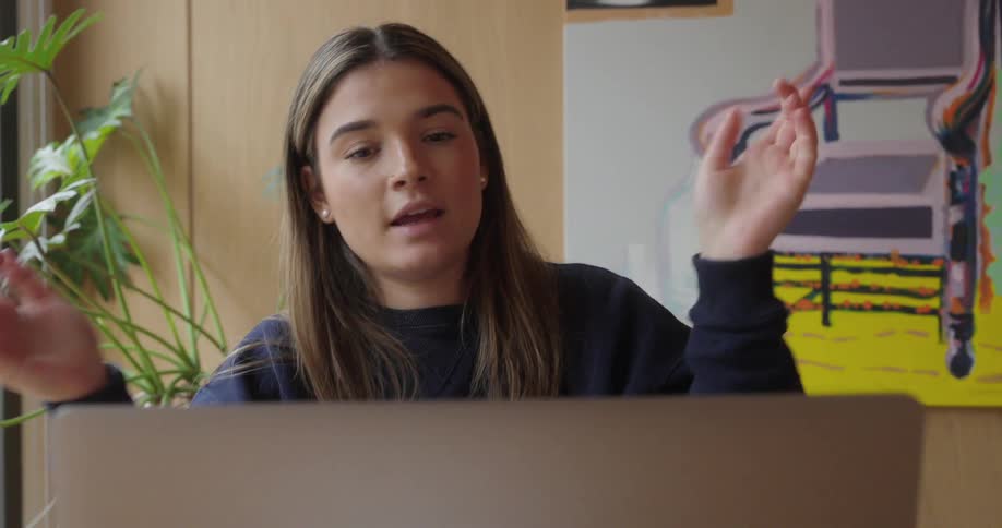 Woman making hand signals in front of a laptop