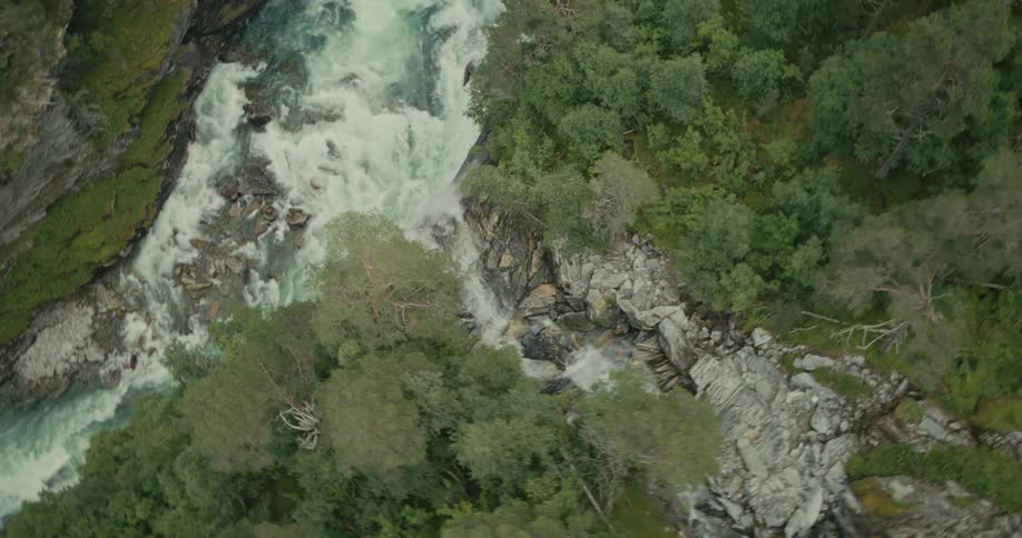 Aerial waterfall flowing into rapid rushing river in canyon