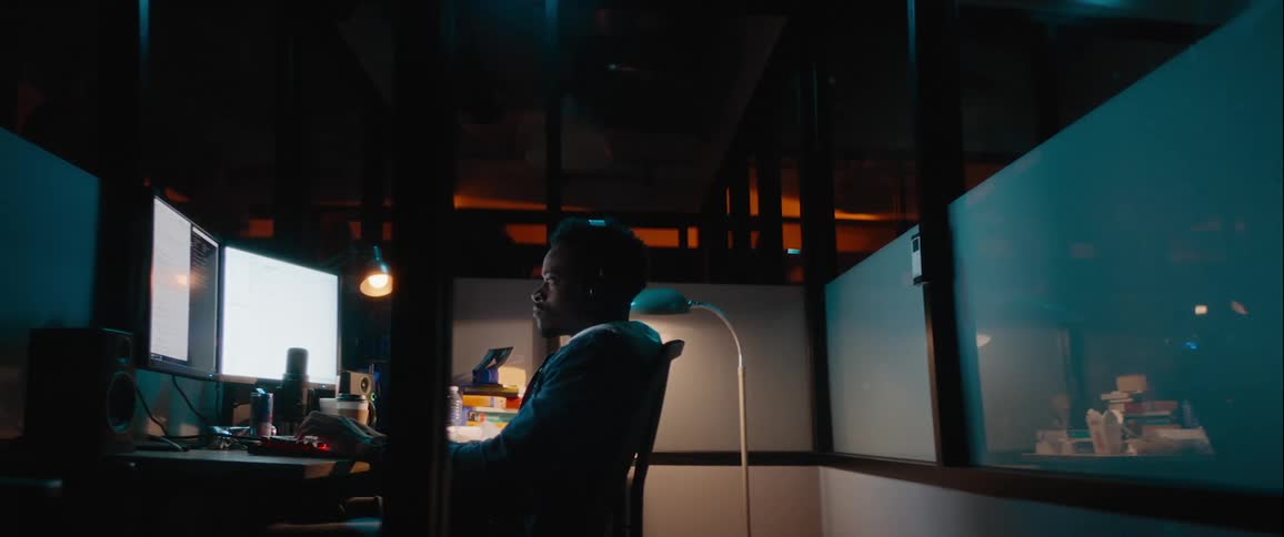 Man working late at the office turns to look around when the ceiling lights come on