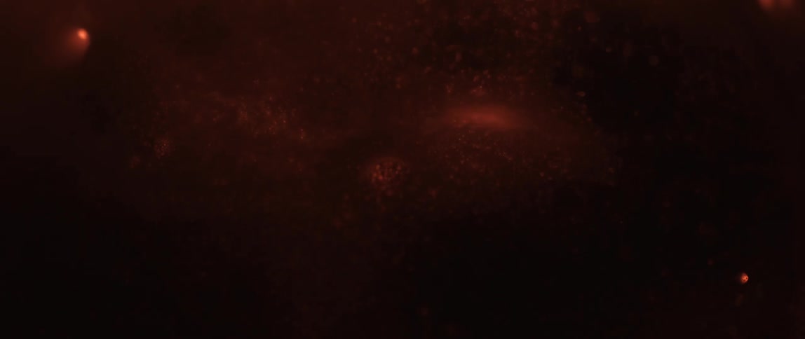 Dim orange particles floating against a dark background